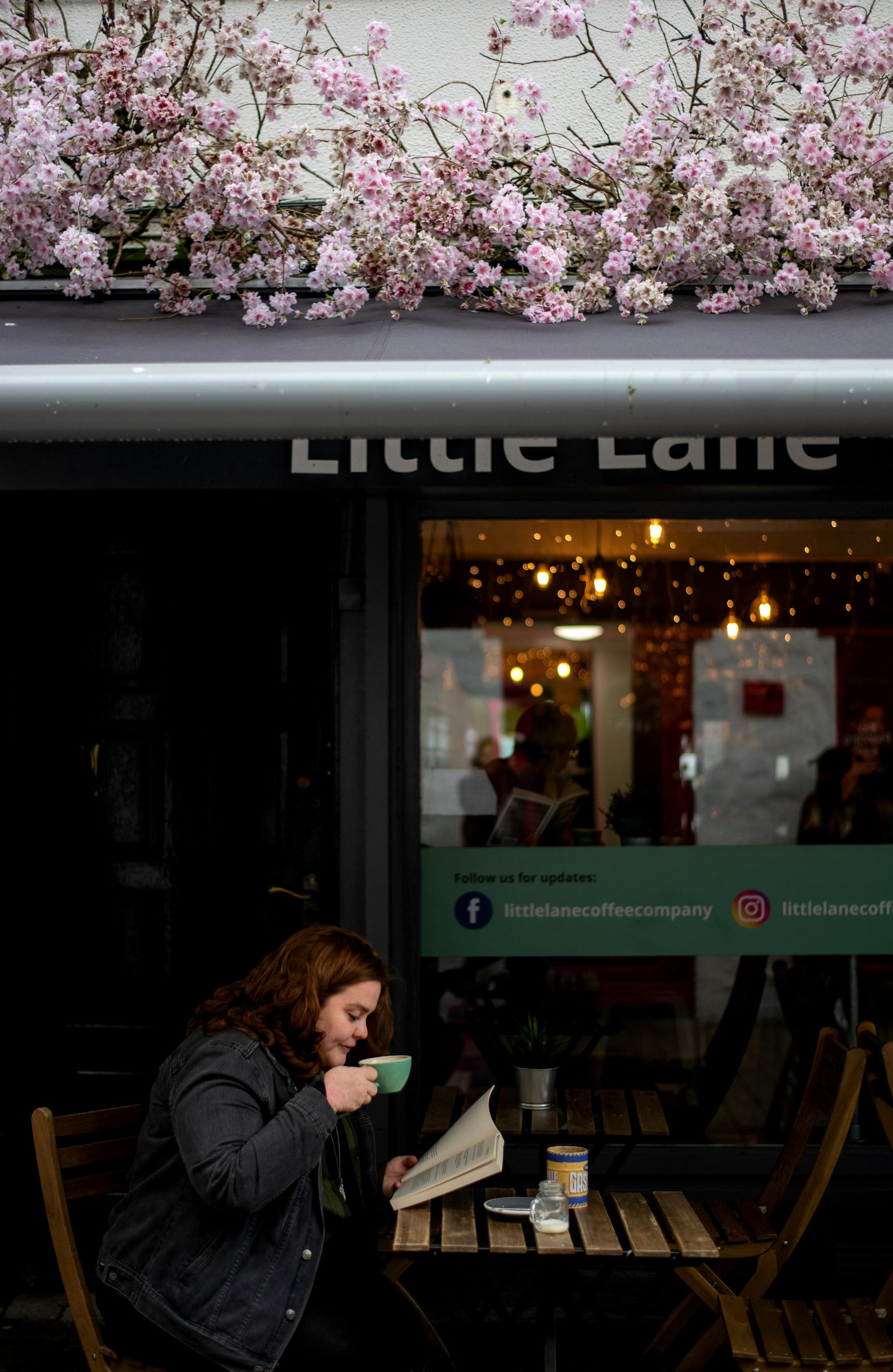 young woman sips coffee at a cafe in Ireland